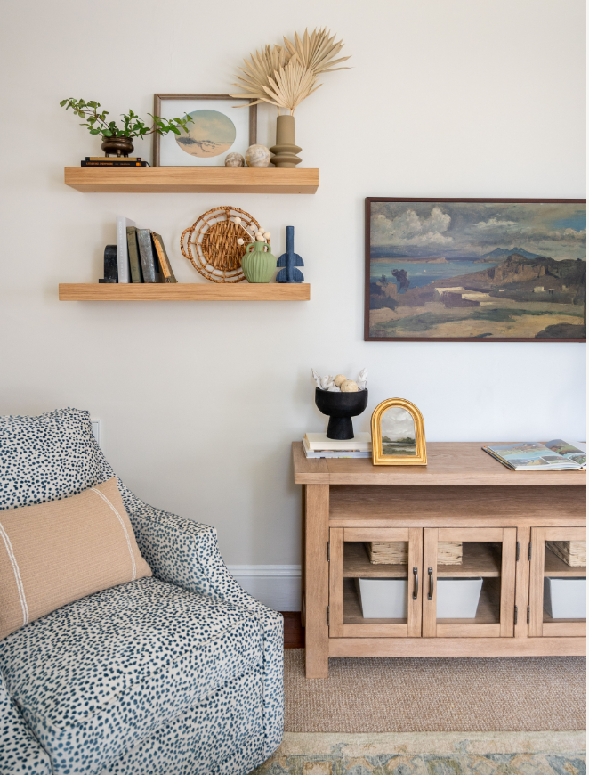 Styled open shelving by a TV and console table with a custom upholstered swivel chair. 